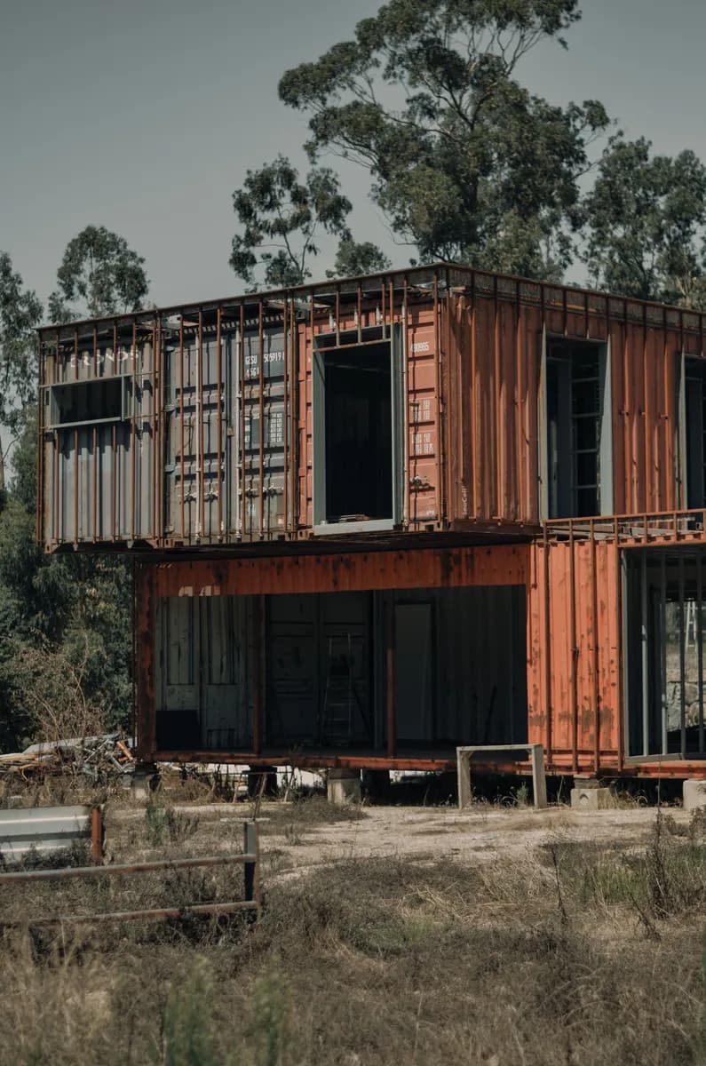 BookNoFees-voorbeeldfoto: Containerhuis met twee verdiepingen en grote ramen tussen de bomen