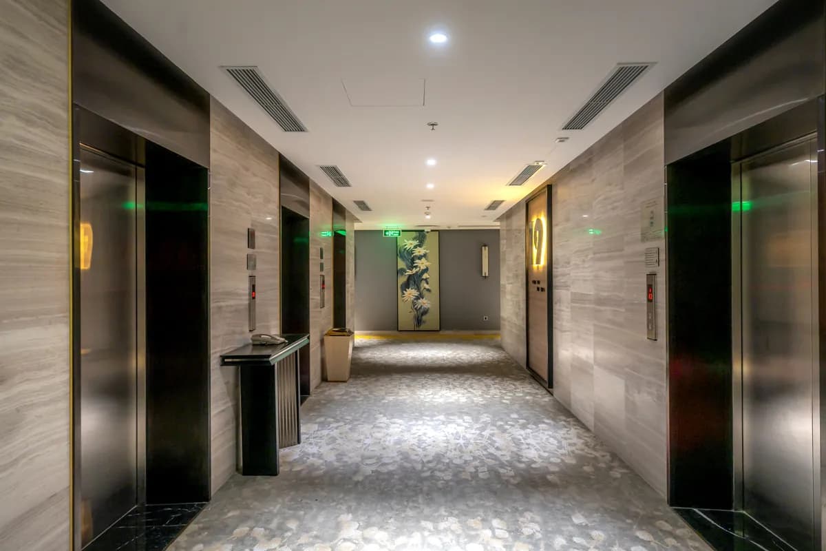 BookNoFees-voorbeeldfoto: hotelgang met liften en grijs tapijt