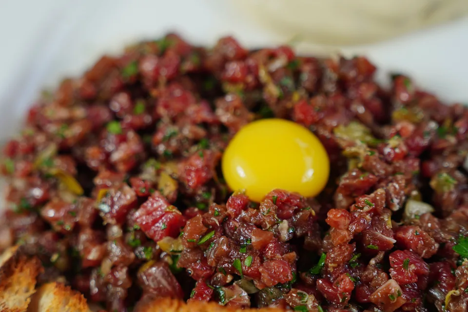 BookNoFees: Voorbeeldfoto: Steak tartaar gegarneerd met eigeel en geserveerd met geroosterd brood