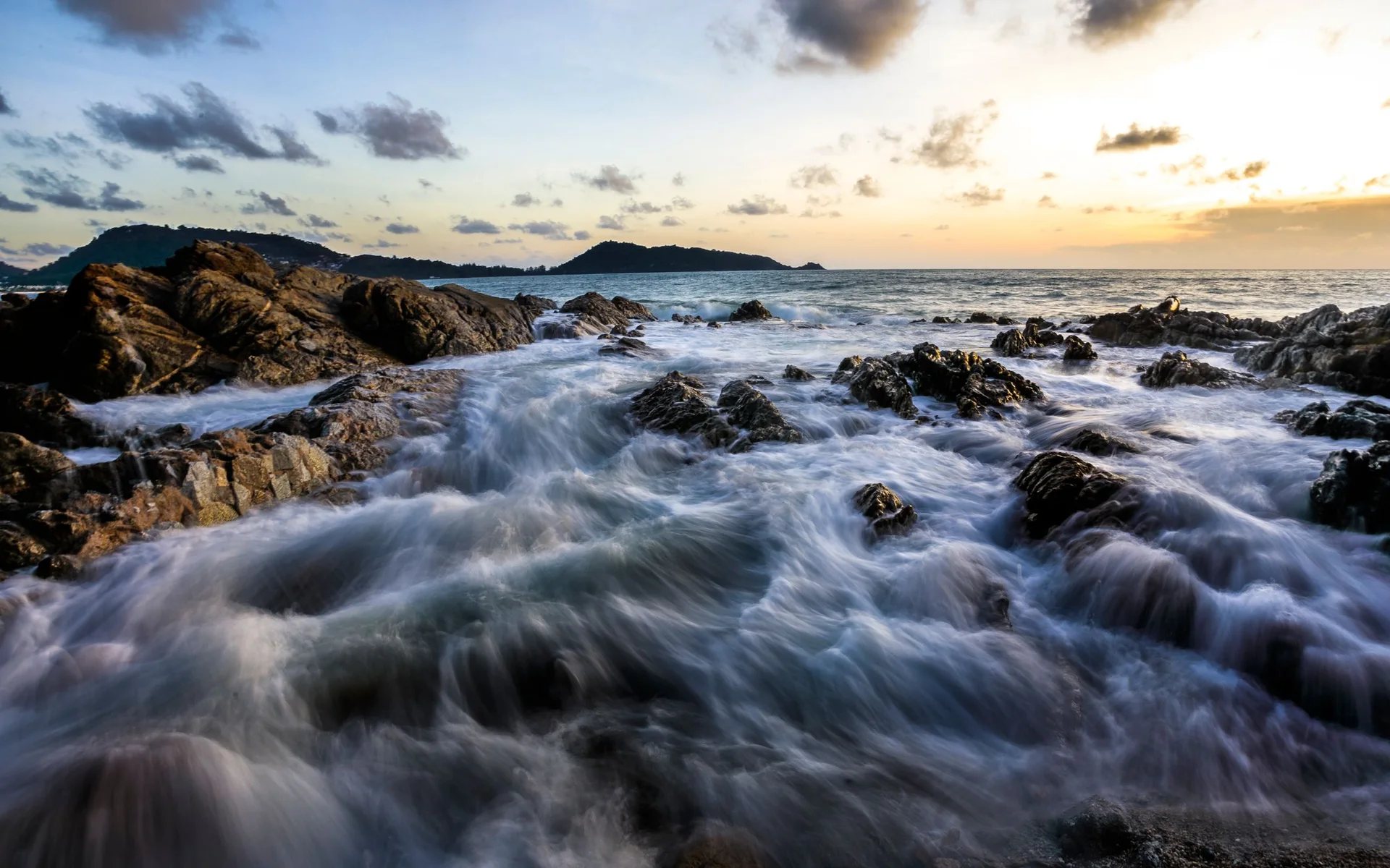 Golven aan de rotskust van Phuket bij zonsondergang