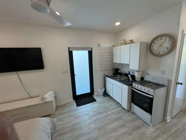 BookNoFees: vakantiehuis in Cutler Bay, Verenigde Staten – Studio-keuken met witte kasten, een gasfornuis, een wandklok en een glazen deur
