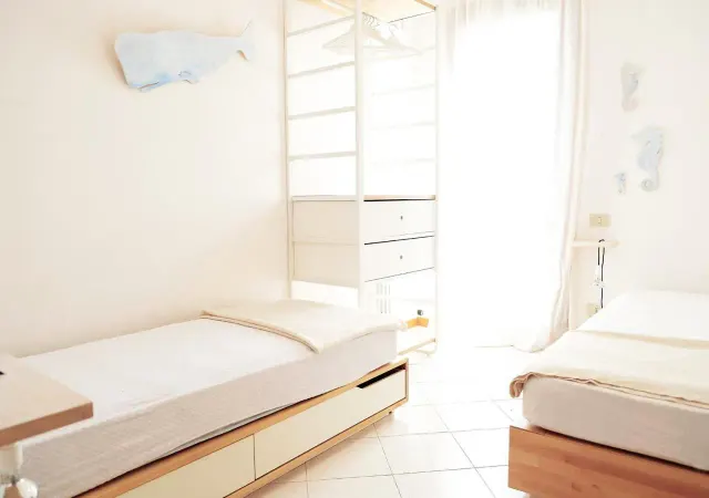 BookNoFees: vakantiehuis in Cavallino-Treporti, Italië – twee bedden in een slaapkamer met witte muren in het Sunny Apartment On The Sea in Cavallino-Treporti