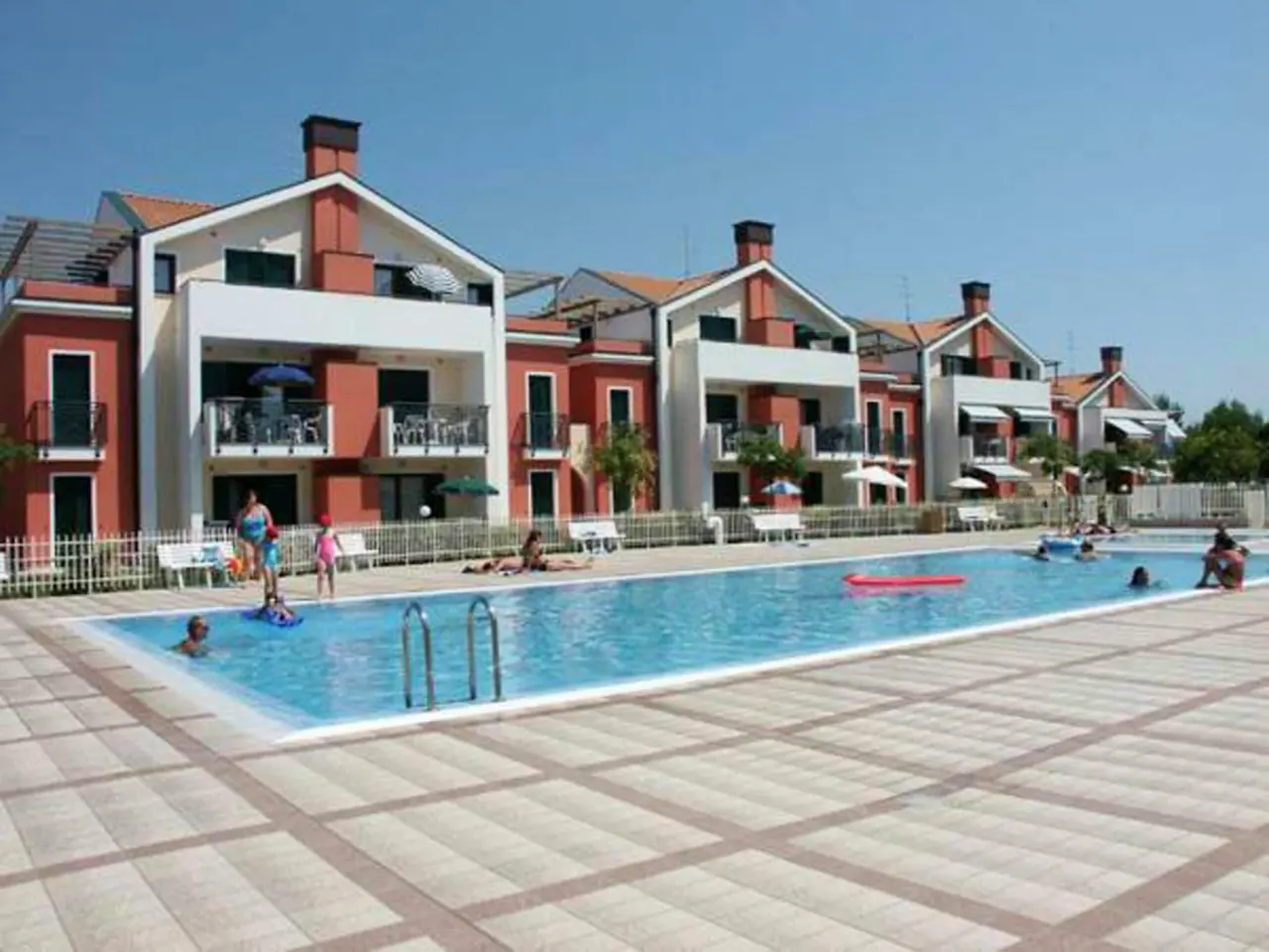 BookNoFees: vakantiehuis in Cavallino-Treporti, Italië – een groep mensen in een zwembad naast de gebouwen van Sunny Apartment On The Sea in Cavallino-Treporti