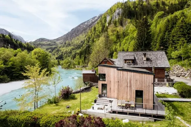 BookNoFees: vakantiehuis in Hieflau – Buitenzicht van een houten vakantiehuis met de rivier en de bergen op de achtergrond