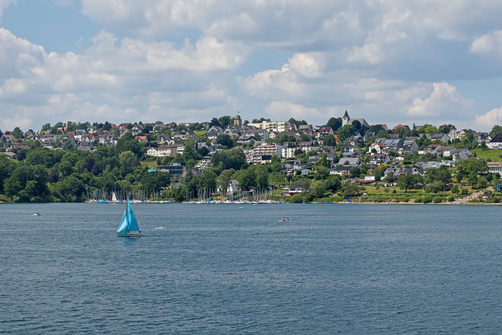 Langscheid aan de Sorpesee bij Sundern: het dorp aan het meer, hoog boven het water, met een zeilboot op de voorgrond
