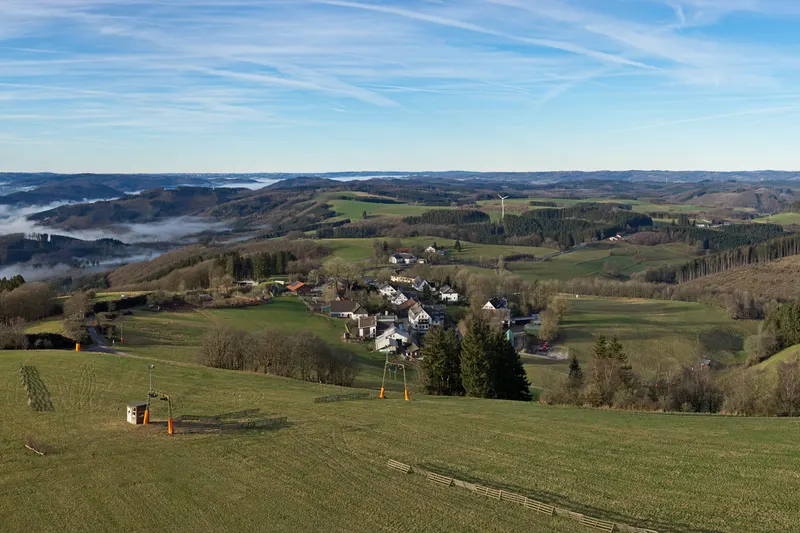 Wildewiese in de heuvels van het Sauerland, met een skilift op de weide en het dorp beneden