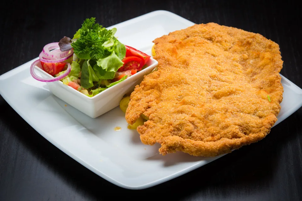 BookNoFees: Voorbeeldfoto: Gepaneerde schnitzel met een salade erbij op een wit bord