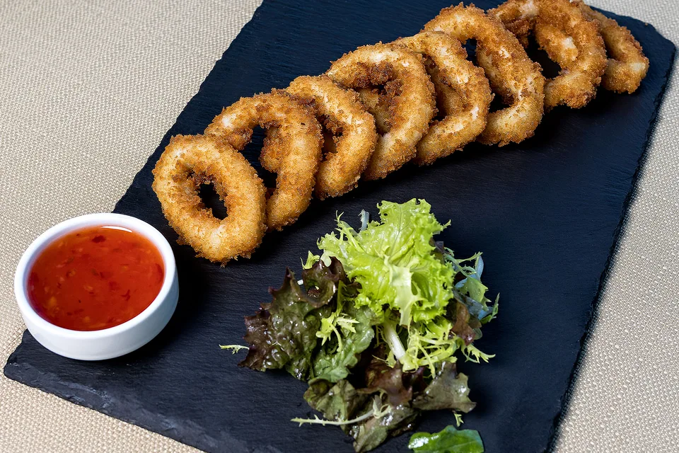 Voorbeeldfoto: Gefrituurde calamaresringen met salade en dipsaus