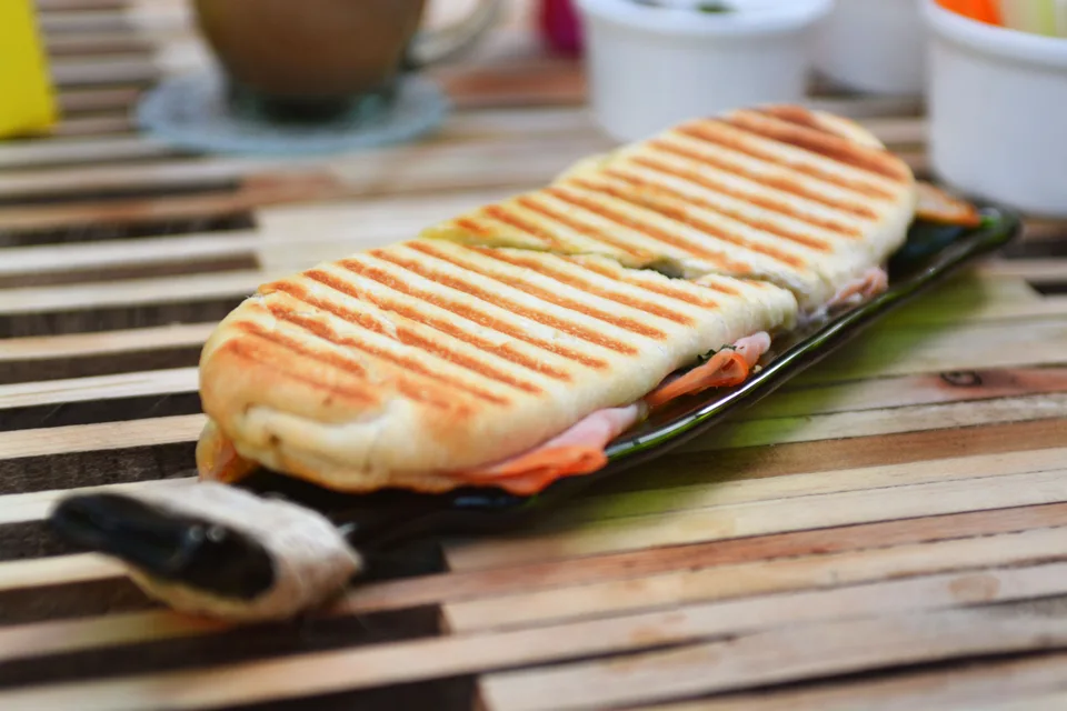 Voorbeeldfoto: Een geroosterde panini met grillstrepen op een donker bord