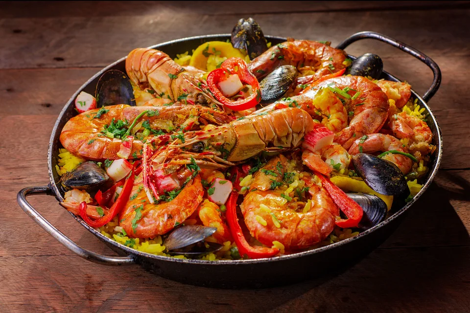 BookNoFees: Voorbeeldfoto: Een pan met paella met zeevruchten, gegarneerd met schaaldieren en rode paprika’s